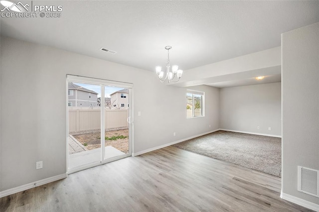 7718 Benecia Dr, Fountain, CO 80817 - unfurnished room featuring visible vents, baseboards, an inviting chandelier, and wood finished floors