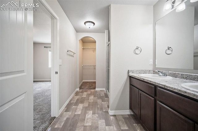 7718 Benecia Dr, Fountain, CO 80817 - bathroom featuring a spacious closet, double vanity, a sink, and wood finished floors