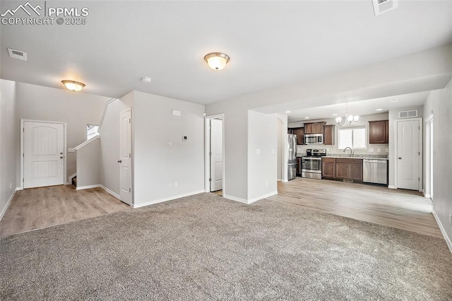 7718 Benecia Dr, Fountain, CO 80817 - unfurnished living room featuring a chandelier, visible vents, and light colored carpet