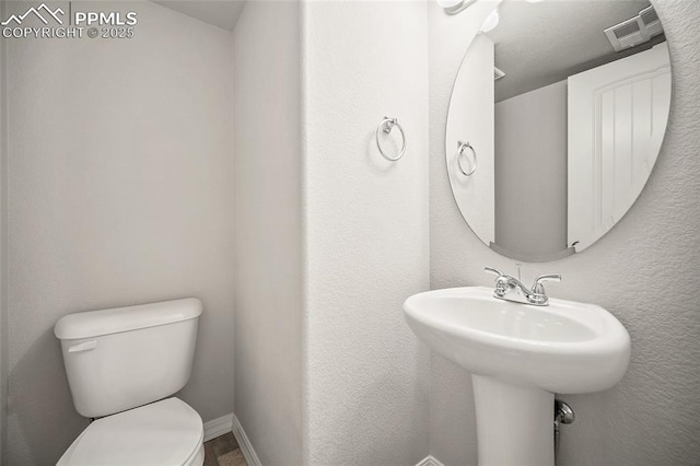 7718 Benecia Dr, Fountain, CO 80817 - half bath featuring visible vents, toilet, a sink, a textured wall, and baseboards