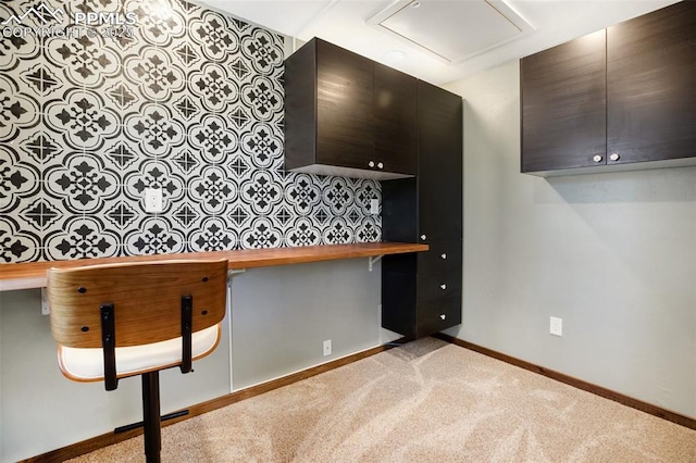 kitchen featuring baseboards, carpet floors, built in desk, and wood counters