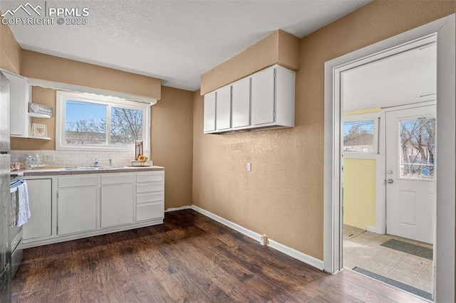 224 W Mill St, Colorado Springs, CO 80903 - kitchen with baseboards, dark wood-style flooring, white cabinets, and a textured wall