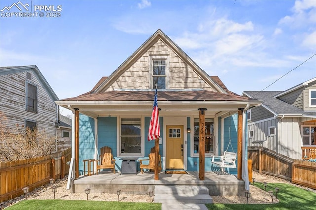 view of front of property with fence private yard, a porch, and a shingled roof