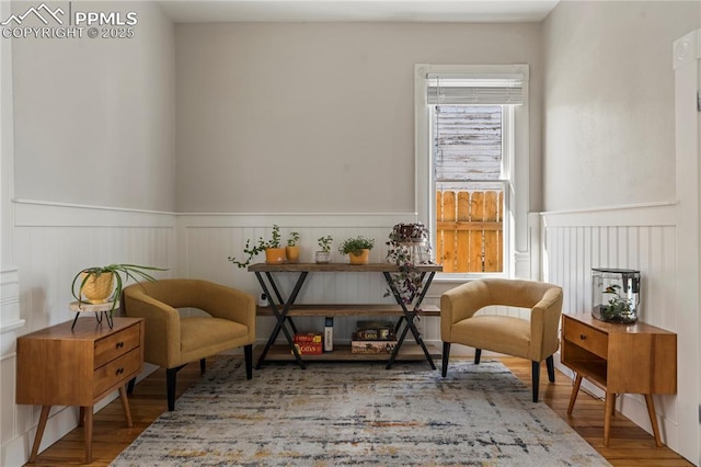 living area with a wainscoted wall and wood finished floors