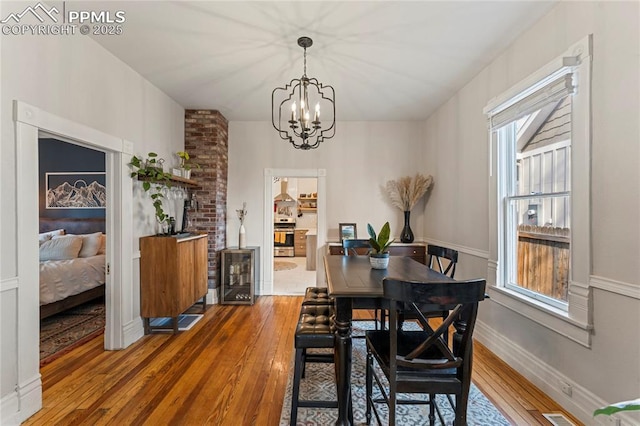 dining room with hardwood / wood-style flooring, beverage cooler, a chandelier, and a healthy amount of sunlight