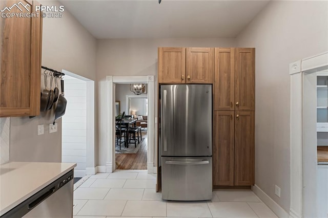 kitchen featuring baseboards, a chandelier, appliances with stainless steel finishes, light countertops, and light tile patterned floors