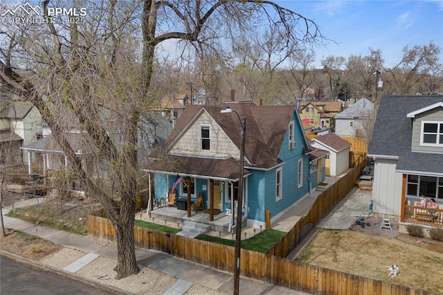 view of front of house with a fenced front yard, a residential view, covered porch, and a shingled roof