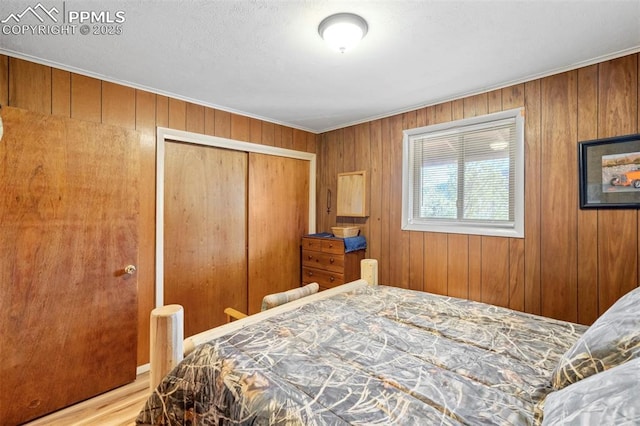 bedroom with a closet, wood walls, and crown molding