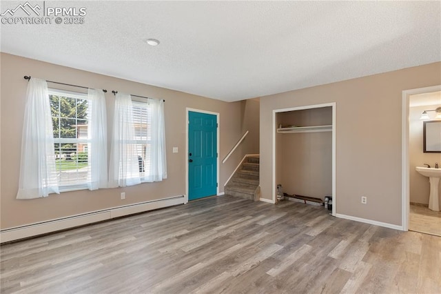 1187 Willow Bend Cir Unit A # 4, Colorado Springs, CO 80918 - unfurnished living room featuring baseboard heating, light wood-style floors, stairway, and a textured ceiling