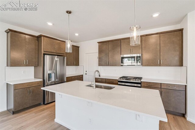 1821 Water Birch Way, Castle Rock, CO 80108 - kitchen with stainless steel appliances, backsplash, hanging light fixtures, a sink, and light wood finished floors