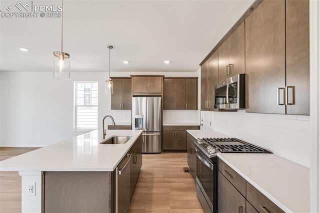 1821 Water Birch Way, Castle Rock, CO 80108 - kitchen with backsplash, a sink, light wood finished floors, dark brown cabinetry, and appliances with stainless steel finishes