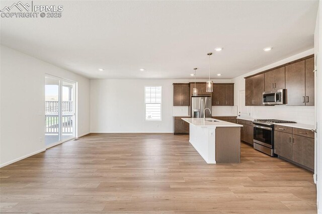 1821 Water Birch Way, Castle Rock, CO 80108 - kitchen with light countertops, light wood-style flooring, stainless steel appliances, a center island with sink, and open floor plan