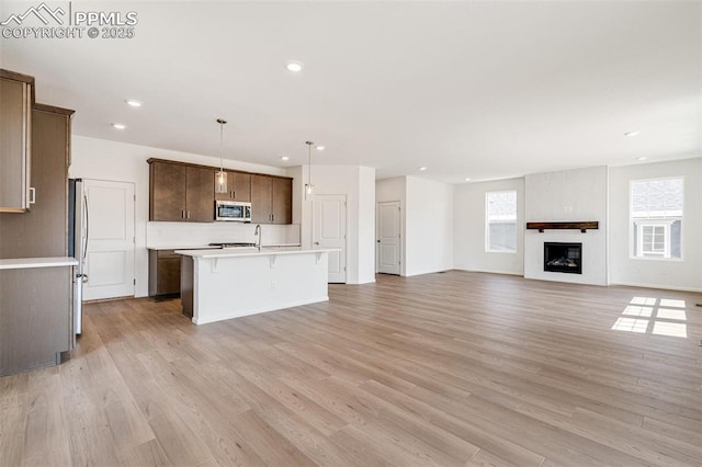 1821 Water Birch Way, Castle Rock, CO 80108 - kitchen featuring light countertops, an island with sink, light wood-style floors, and appliances with stainless steel finishes
