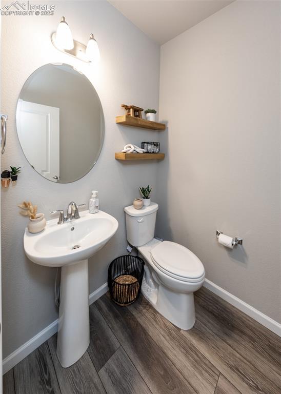 bathroom featuring toilet, baseboards, and wood finished floors