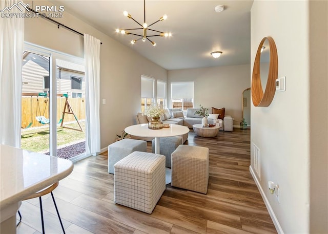 dining space featuring baseboards, a notable chandelier, visible vents, and wood finished floors