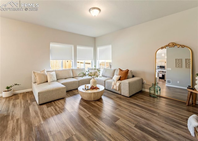 living area with arched walkways, baseboards, visible vents, and wood finished floors