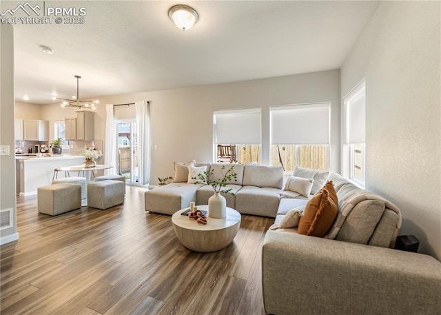 living room featuring an inviting chandelier, visible vents, and wood finished floors