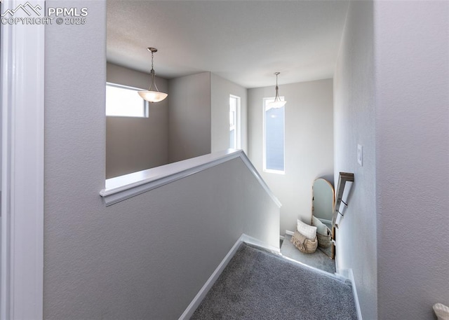 hallway with baseboards, an upstairs landing, and carpet floors