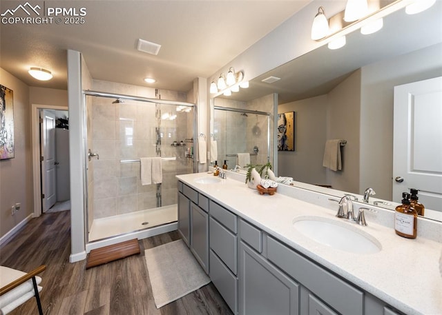 full bath featuring wood finished floors, a sink, visible vents, and a shower stall