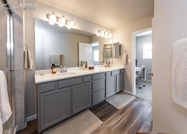 bathroom featuring double vanity, a sink, baseboards, and wood finished floors
