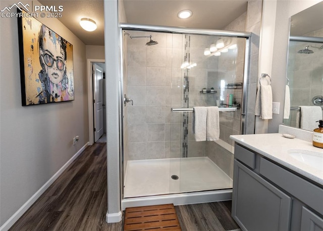 full bathroom with a shower stall, baseboards, wood finished floors, and vanity