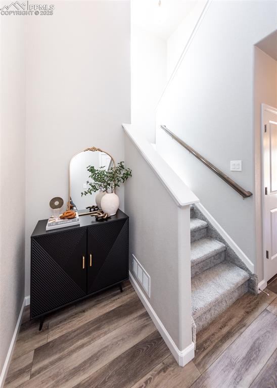 staircase featuring baseboards, visible vents, and wood finished floors