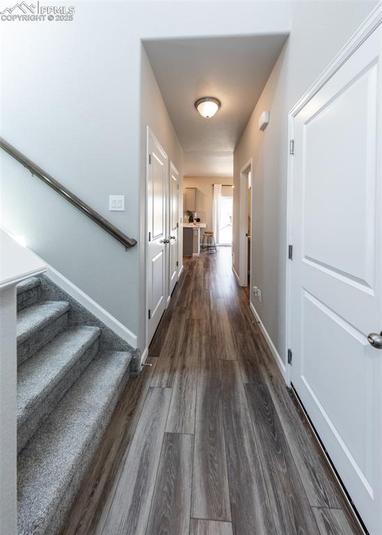 corridor featuring stairs, baseboards, and dark wood-style flooring