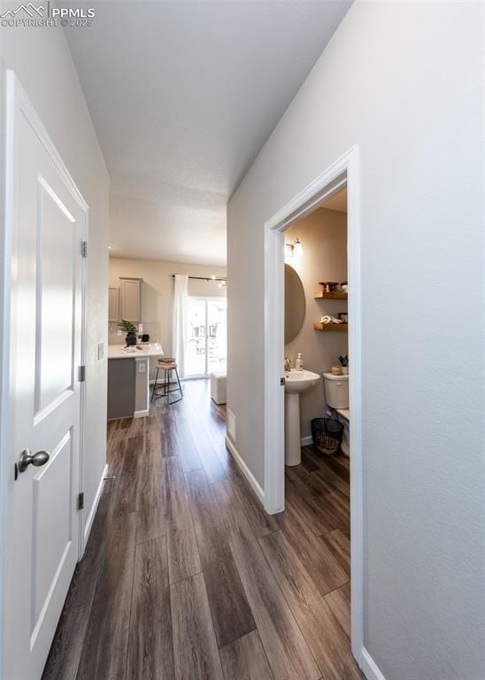 corridor with baseboards and dark wood-style flooring