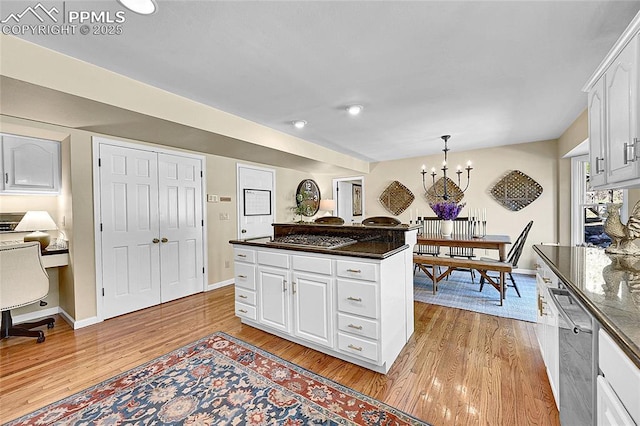 kitchen featuring light wood-style floors, a chandelier, stainless steel appliances, white cabinetry, and baseboards