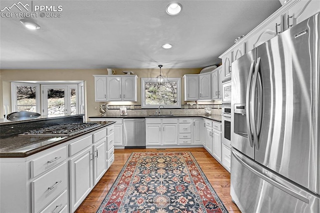 kitchen with appliances with stainless steel finishes, a sink, dark countertops, white cabinetry, and recessed lighting