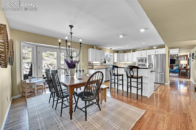 dining space with baseboards, light wood-style flooring, recessed lighting, and a chandelier