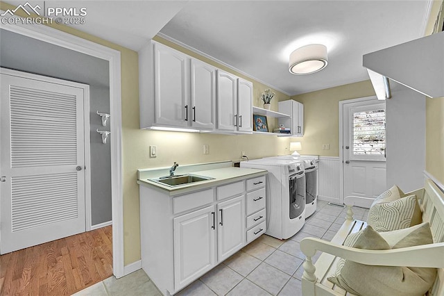 washroom featuring cabinet space, washing machine and clothes dryer, light tile patterned floors, and a wainscoted wall