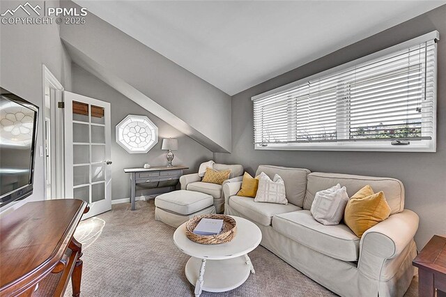 carpeted living area with vaulted ceiling and baseboards
