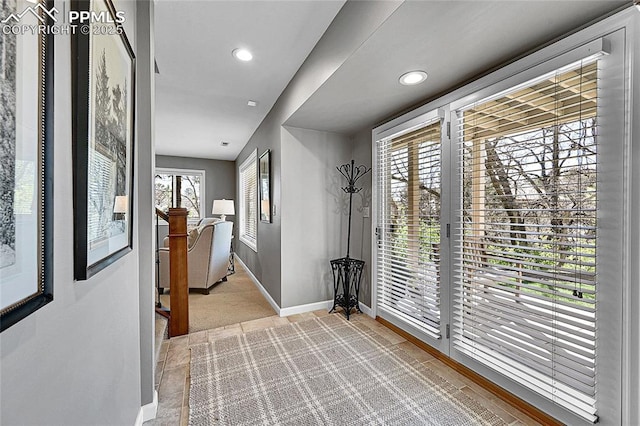 doorway to outside with baseboards, light colored carpet, and recessed lighting