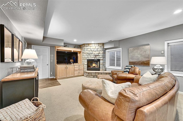 carpeted living area featuring a stone fireplace, recessed lighting, and baseboards