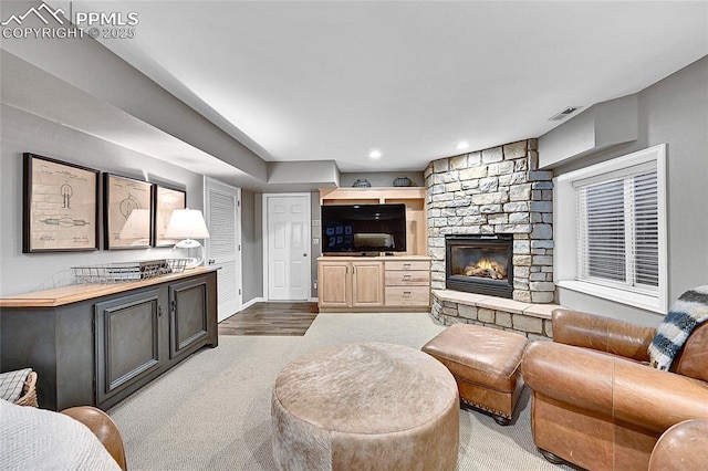 living room with carpet flooring, a stone fireplace, baseboards, and recessed lighting