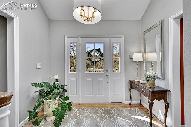 foyer entrance featuring wood finished floors, baseboards, and a chandelier