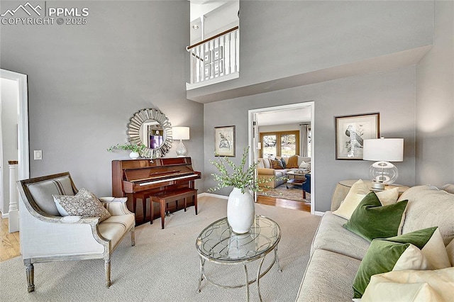 living area featuring a towering ceiling, baseboards, and carpet flooring