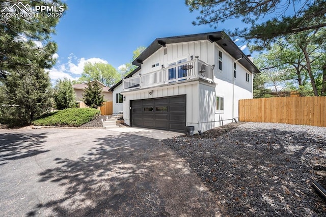 1021 Pioneer Ln, Colorado Springs, CO 80904 - view of front facade featuring a balcony, asphalt driveway, fence, and board and batten siding