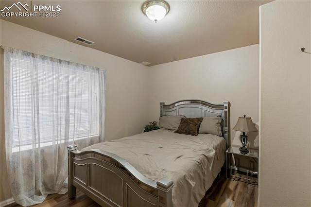bedroom featuring wood finished floors and visible vents