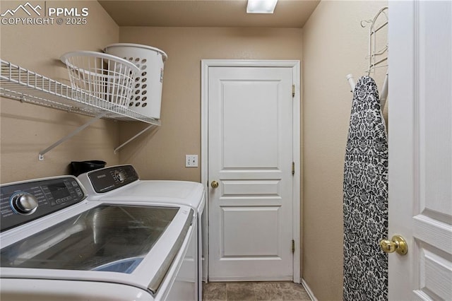washroom with baseboards, washing machine and clothes dryer, and laundry area