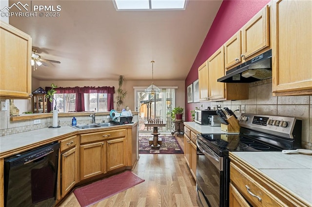 kitchen with a sink, tile countertops, under cabinet range hood, and appliances with stainless steel finishes