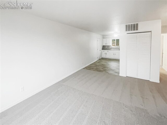 unfurnished living room featuring baseboards, visible vents, and light colored carpet