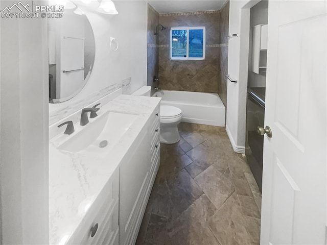 bathroom featuring toilet, stone finish floor, vanity, and shower / washtub combination