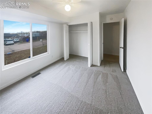 unfurnished bedroom featuring carpet flooring, baseboards, visible vents, a ceiling fan, and a closet