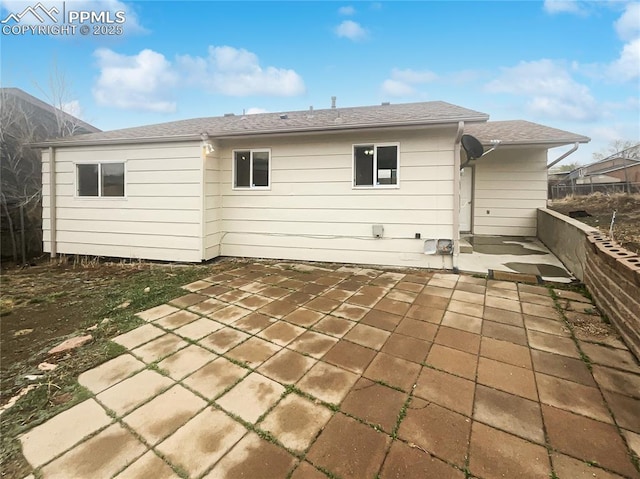 rear view of property with a patio and roof with shingles