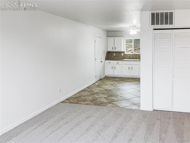 interior space featuring white cabinetry, tasteful backsplash, baseboards, visible vents, and a ceiling fan