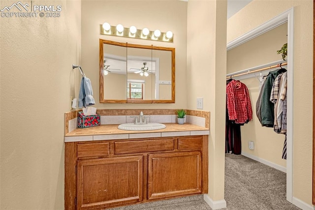 bathroom featuring baseboards, ceiling fan, a spacious closet, and vanity