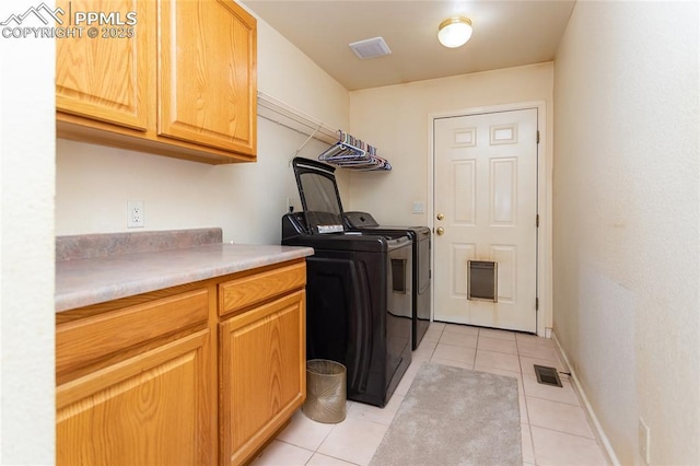 clothes washing area with baseboards, light tile patterned floors, visible vents, cabinet space, and washing machine and clothes dryer