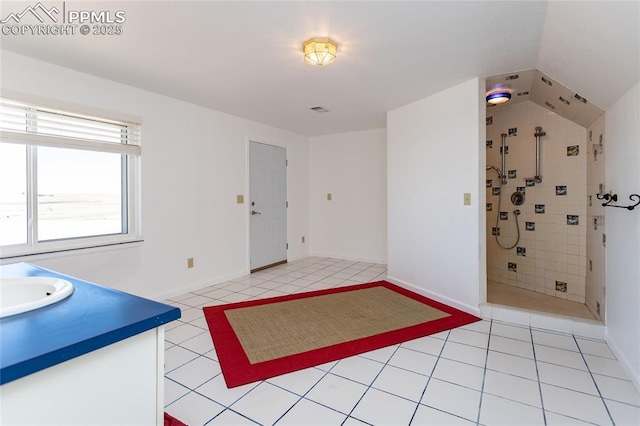 full bath with tile patterned flooring, vanity, baseboards, and tiled shower